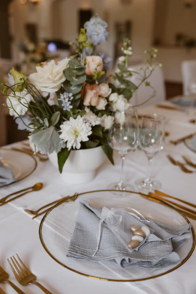ein rustikaler Tisch gedeckt mit gold-weißen Tellern und goldenem Besteck.