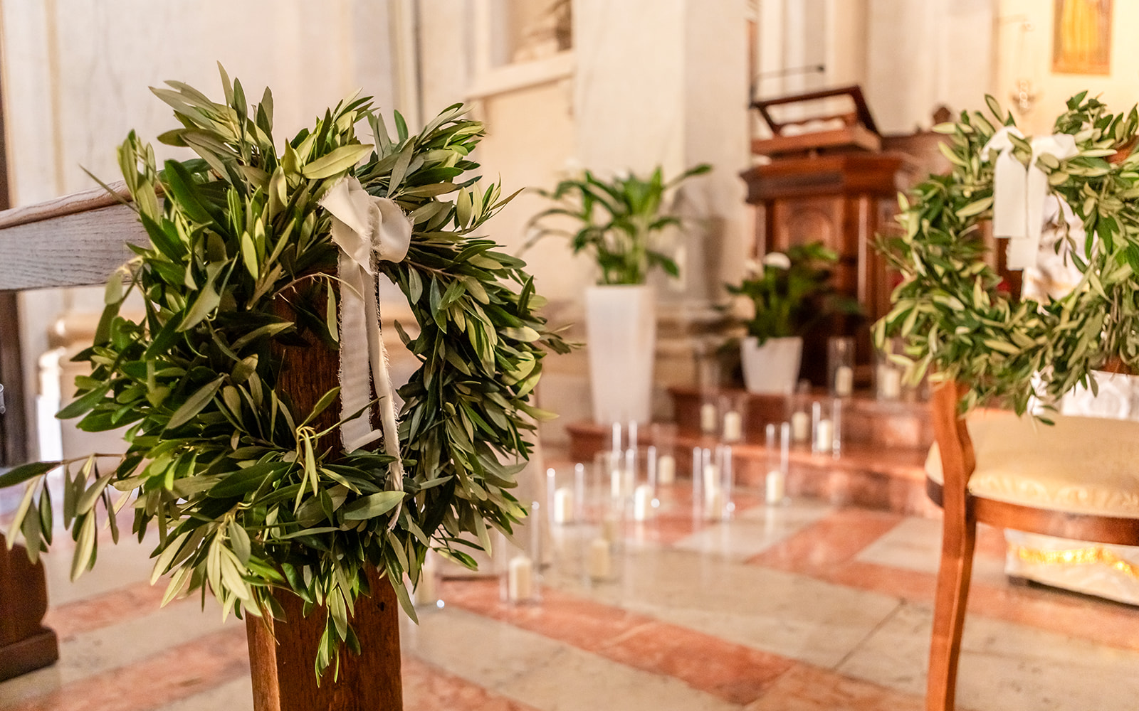 Ein Grüner Granz um die Bank in einer Kirche . im Hintergrund stehen runde gläser mit Kerzen